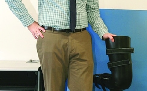 Robert Gregg博士站在由UTDesign学生设计的机械腿旁边，这与他研究中报道的机械腿相似